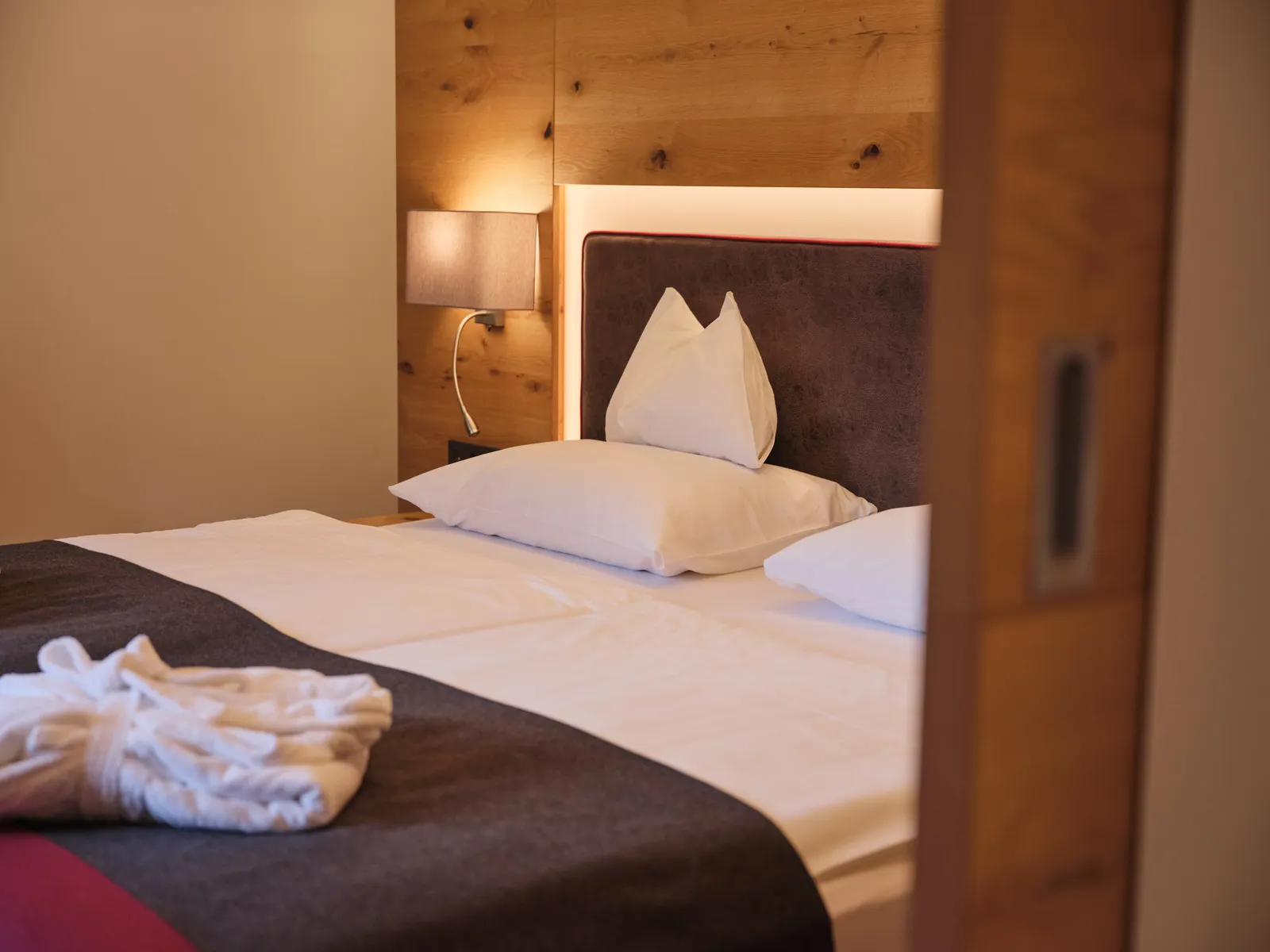 Hotelzimmer mit Doppelbett, Nachttischlampe und Holzwand
