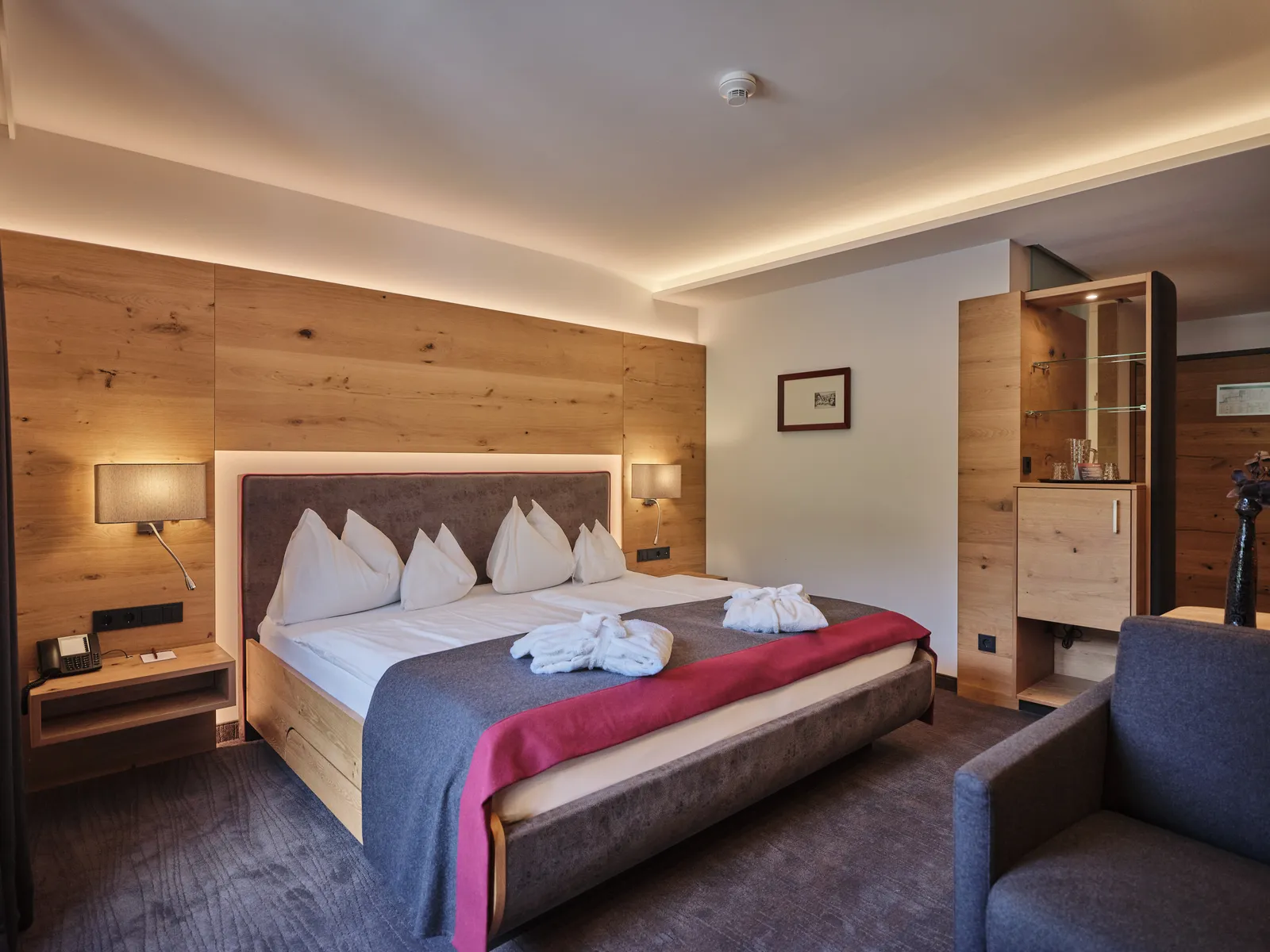 Hotelzimmer mit Doppelbett, Holzwand und indirekter Beleuchtung