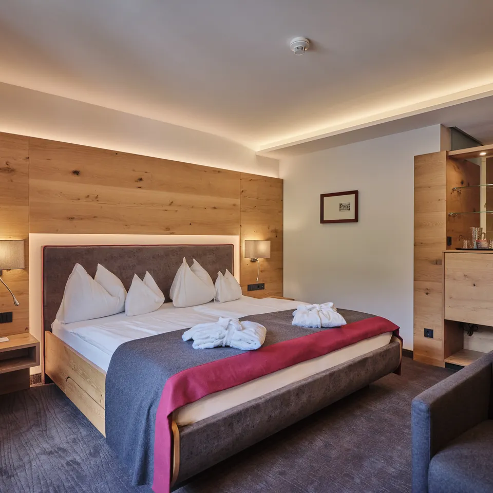Hotelzimmer mit Doppelbett, Holzwand und indirekter Beleuchtung
