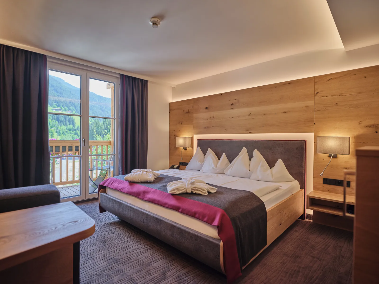 Hotelzimmer mit Doppelbett, Balkon und Holzwand