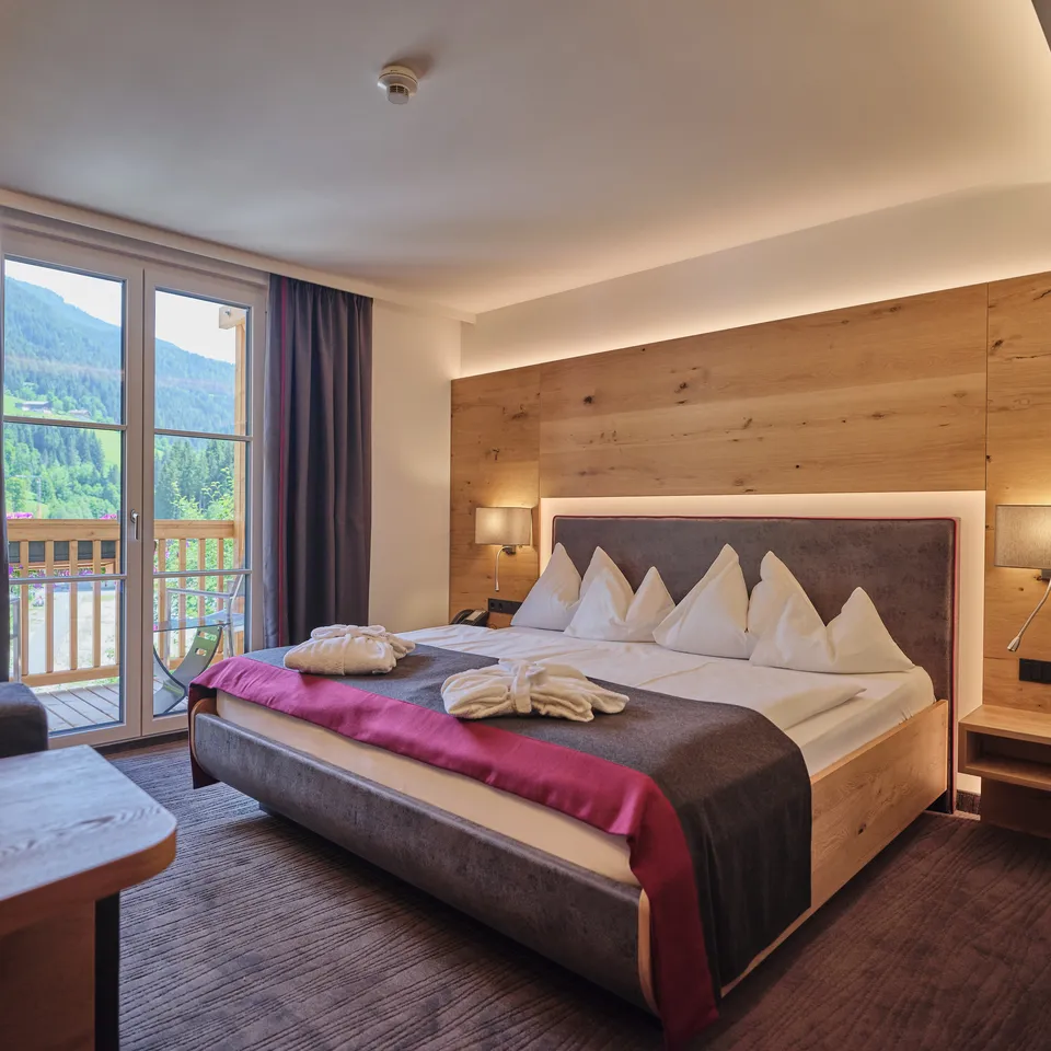 Hotelzimmer mit Doppelbett, Balkon und Holzwand