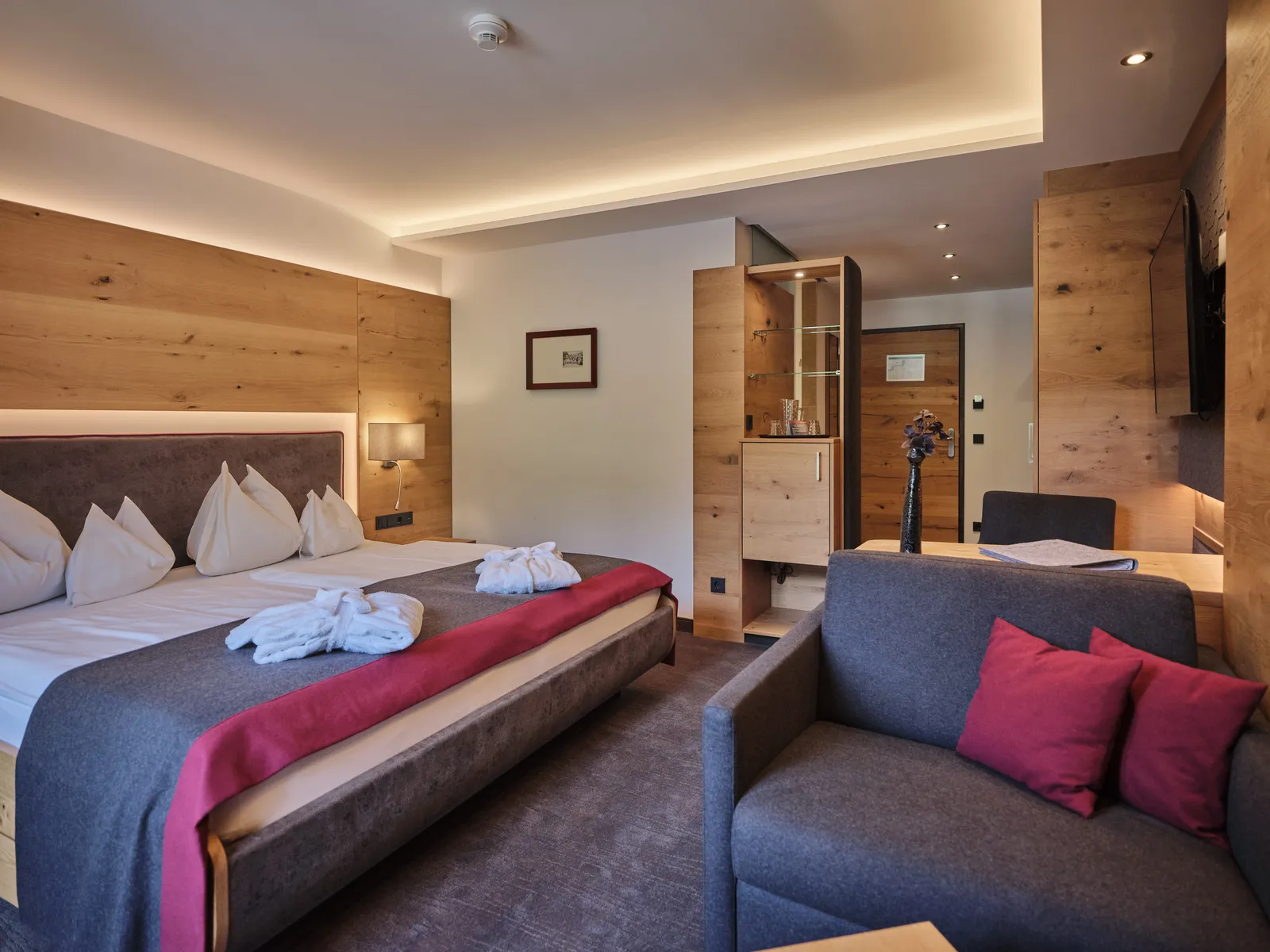Hotelzimmer mit Doppelbett, Sofa und Holzvertäfelung