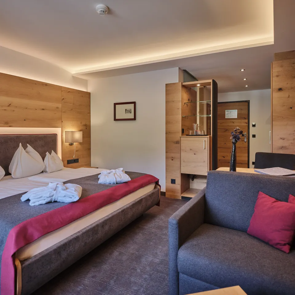Hotelzimmer mit Doppelbett, Sofa und Holzvertäfelung