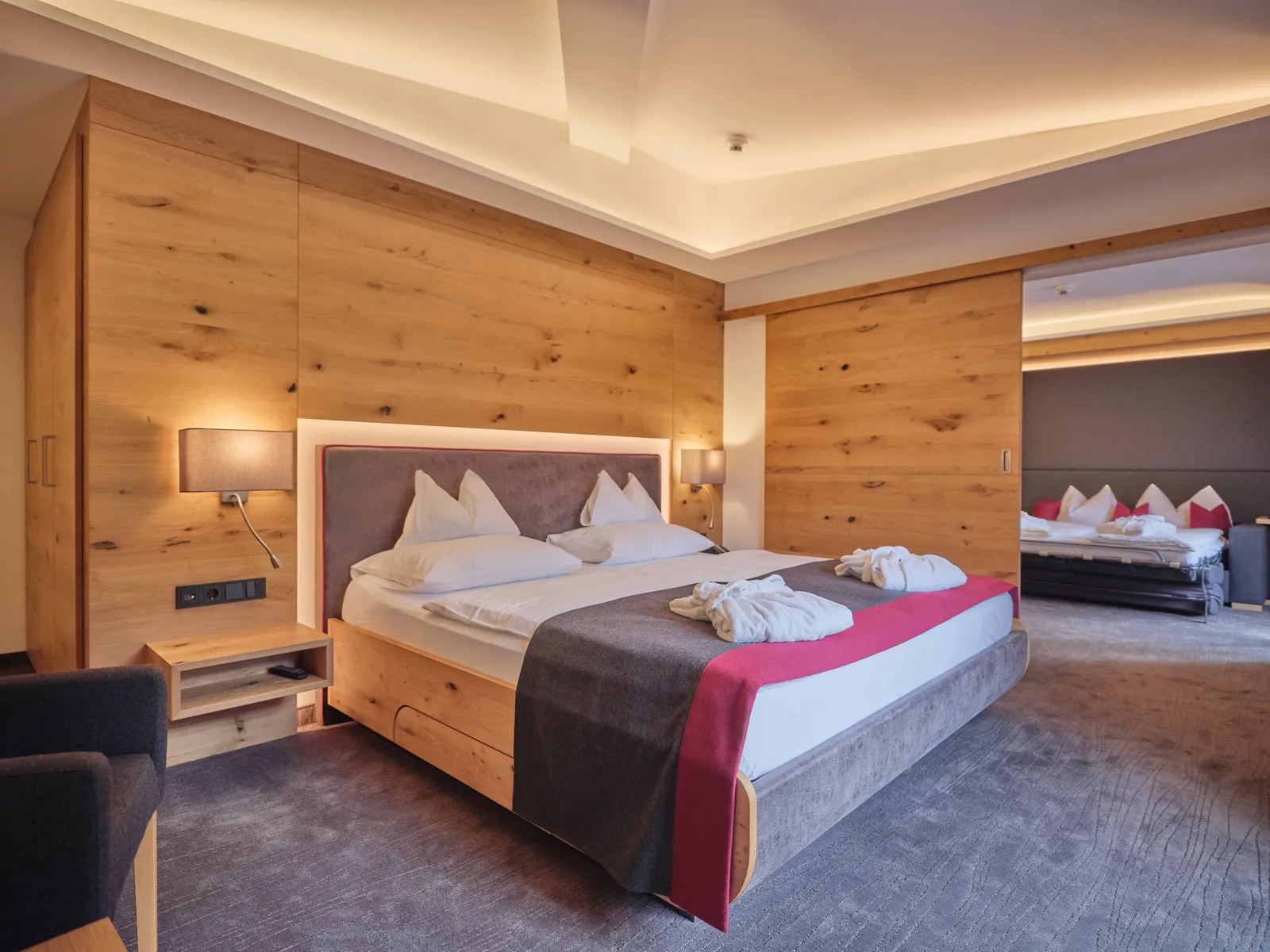 Helles Hotelzimmer mit Doppelbett und Holzwand