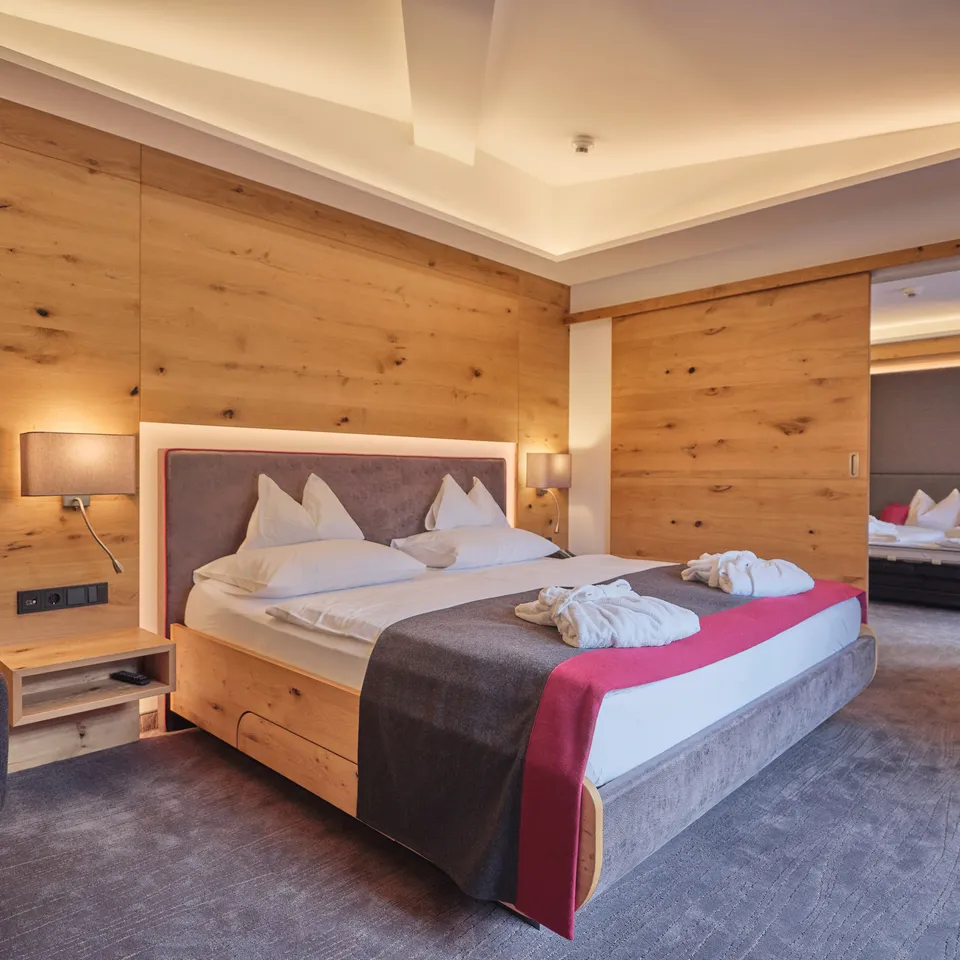 Helles Hotelzimmer mit Doppelbett und Holzwand