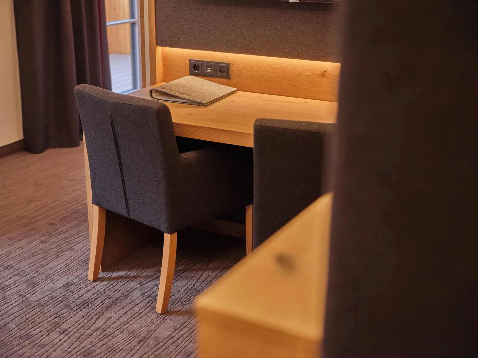Schreibtisch mit Stuhl und Ablage in einem Hotelzimmer
