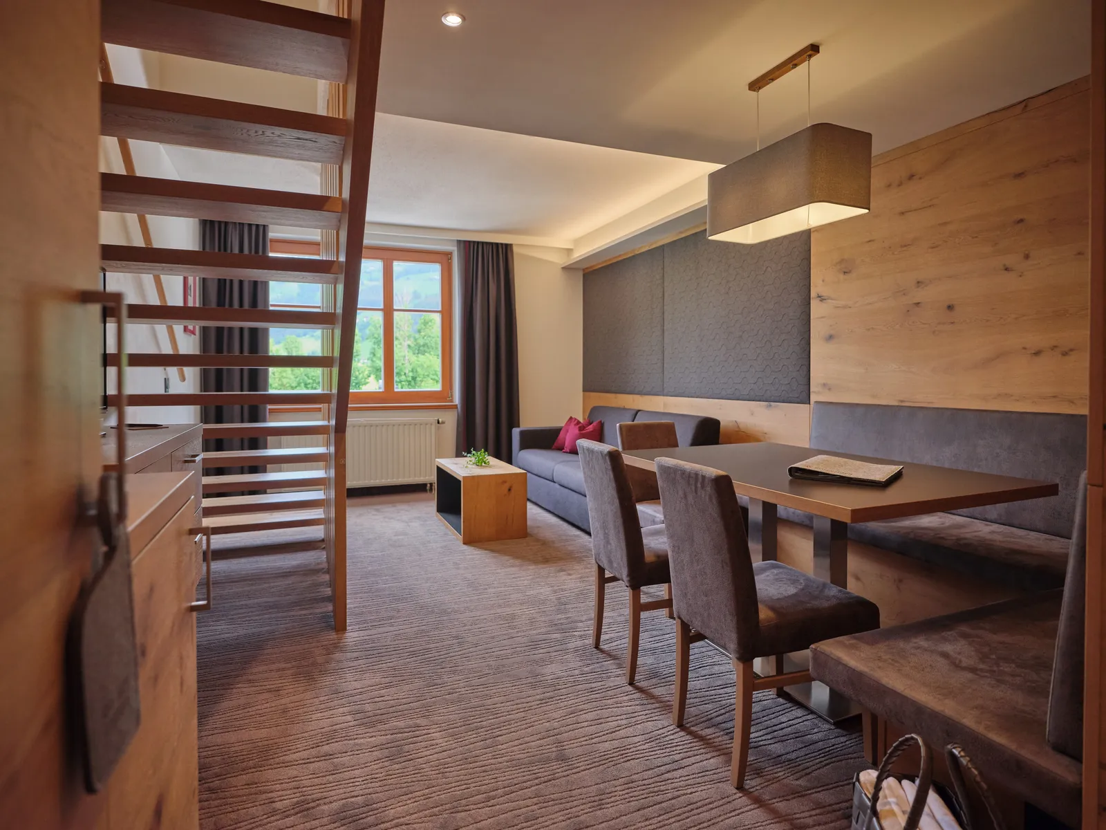 Helles Apartment mit Treppe, Sofa, Tisch, Stühlen und Fenster