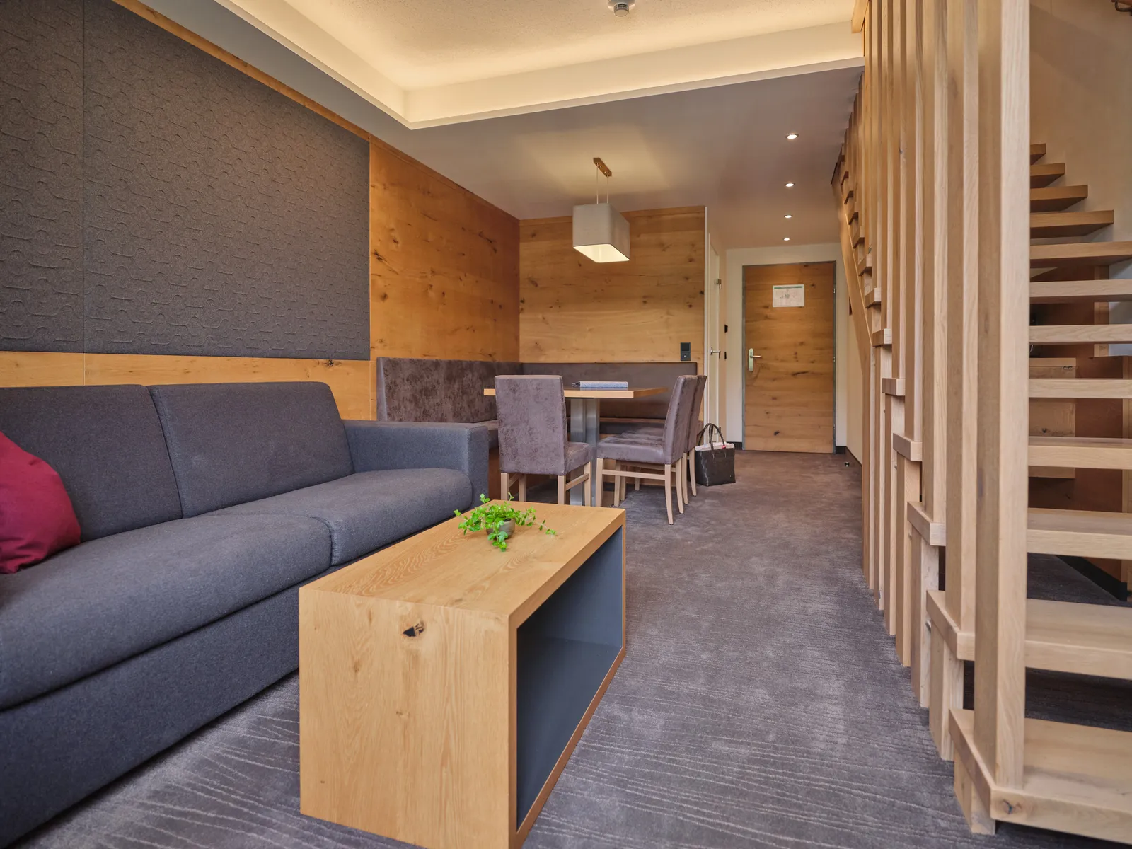 Hotelzimmer mit Sofa, Tisch, Stühlen und Holzelementen