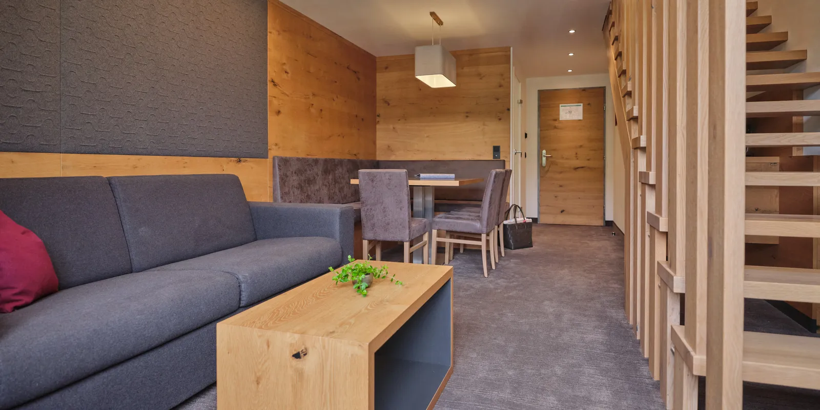 Hotelzimmer mit Sofa, Tisch, Stühlen und Holzelementen