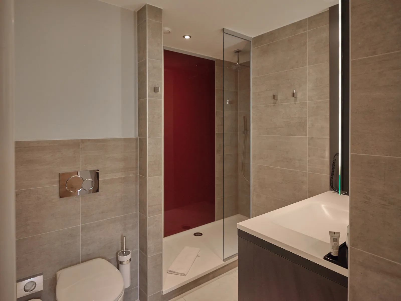 Modernes Badezimmer mit Dusche, WC und Waschbecken in Beige- und Rottönen