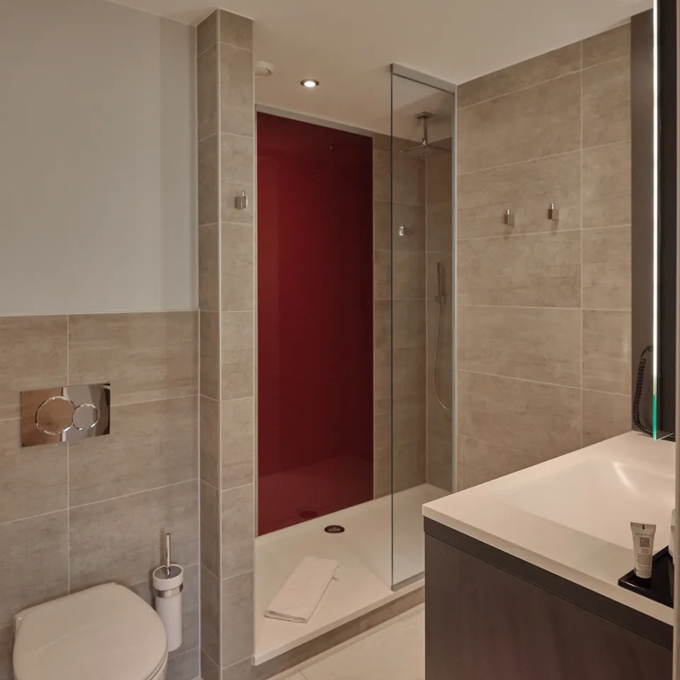 Modern bathroom with shower, toilet and sink in beige and red tones