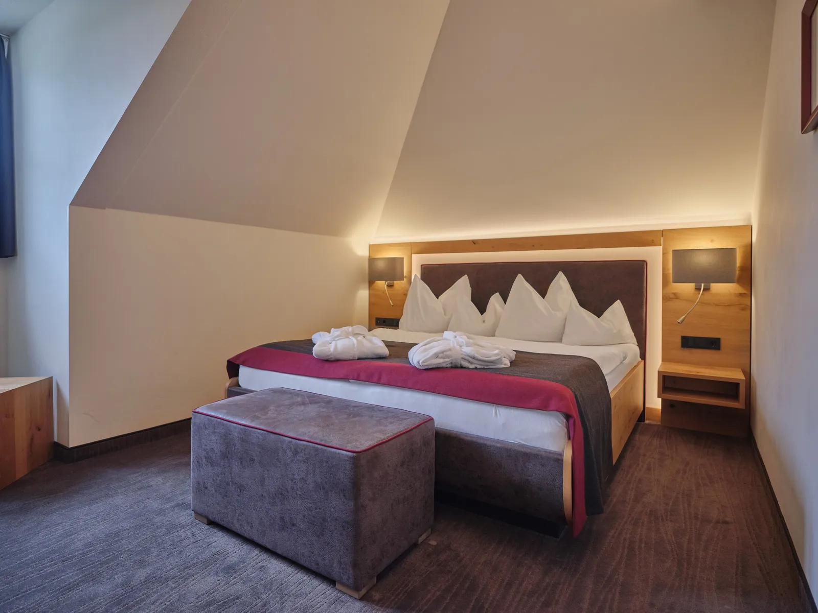 Schlafzimmer mit Doppelbett, Nachttischen und Dachschräge im Sporthotel Wagrain