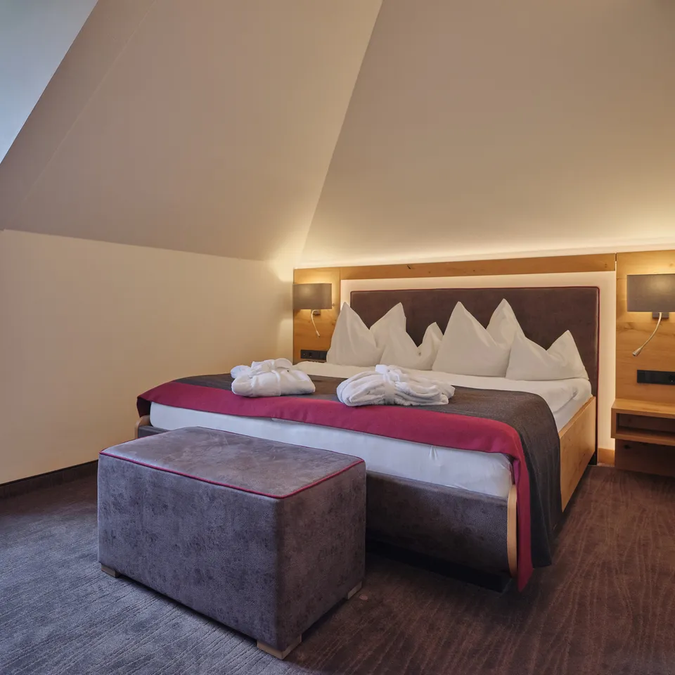Bedroom with double bed, bedside tables and sloping ceiling in the Sporthotel Wagrain