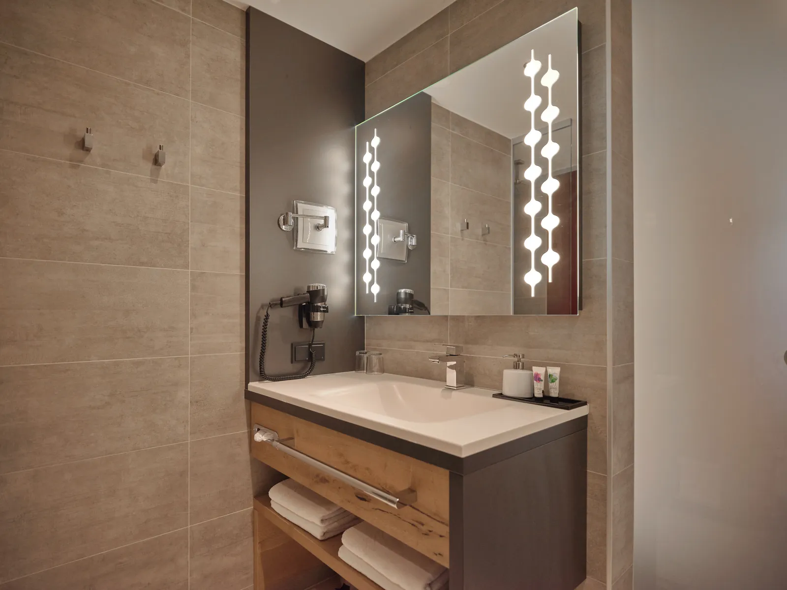 Modernes Badezimmer mit Waschbecken, Spiegel mit Beleuchtung und Handtüchern