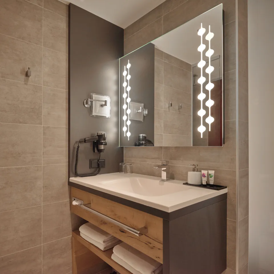Modern bathroom with sink, mirror with lighting and towels
