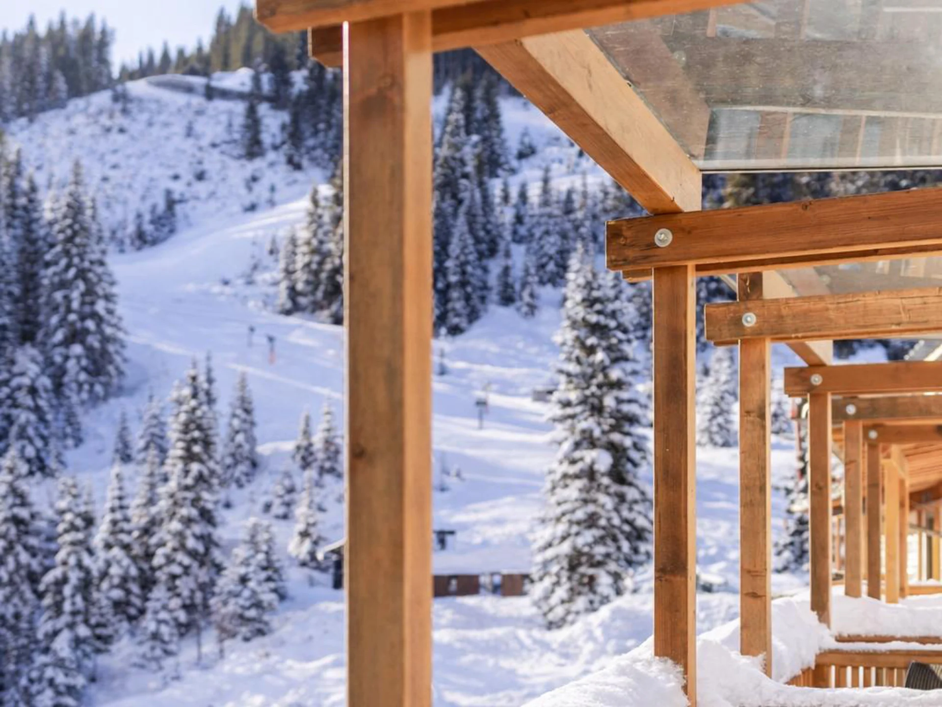 Verschneite Holzterrasse mit Bergblick und Skipiste