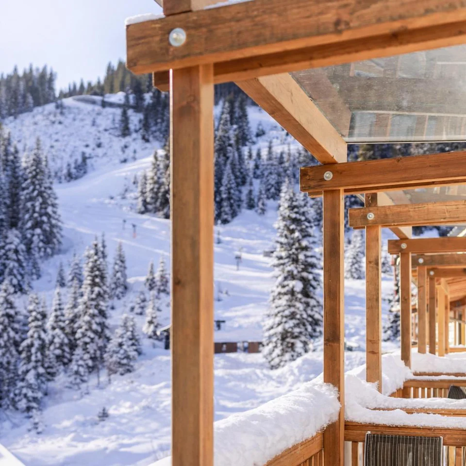 Verschneite Holzterrasse mit Bergblick und Skipiste