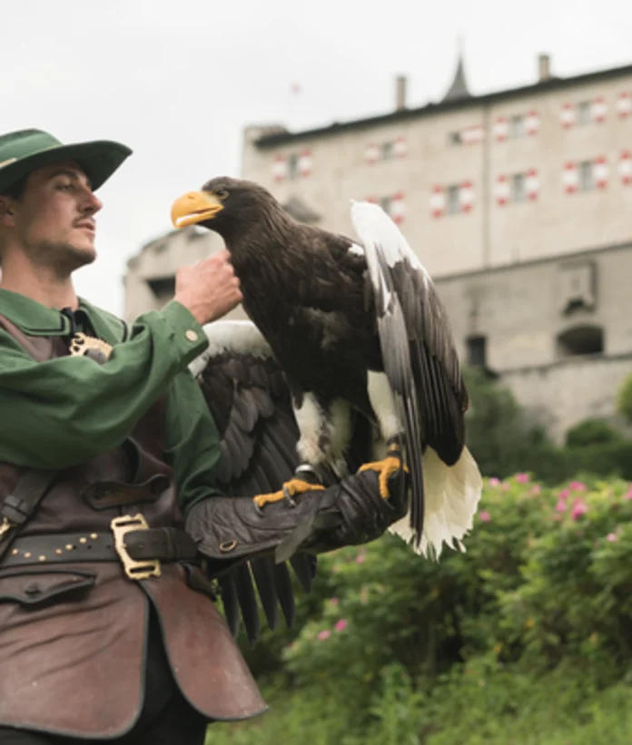 Falkner mit Adler auf der Hand vor Burg Hohenwerfen