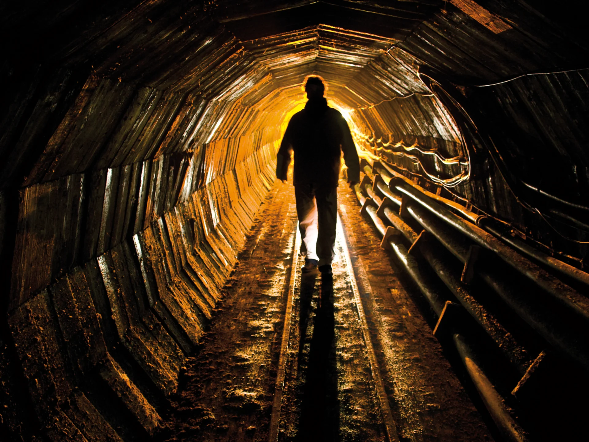 Miner in the tunnel with orange light at the end