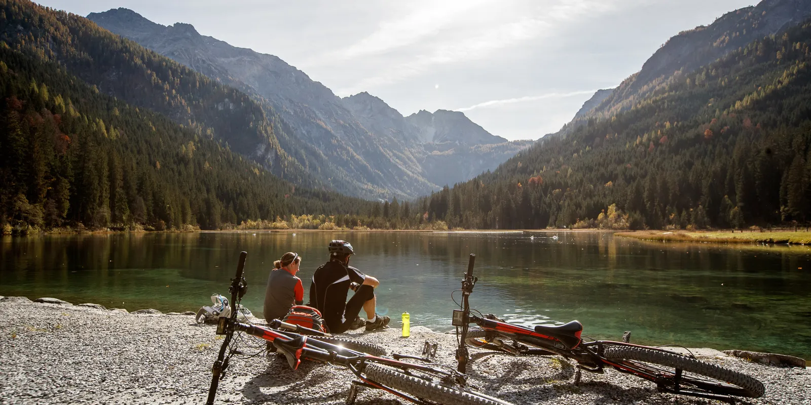Radfahrerpaar macht Pause am Ufer des Jägersees vor Bergkulisse