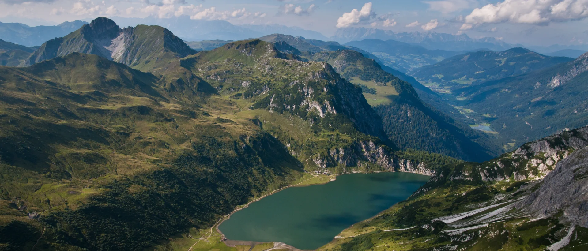Tappenkarsee in Kleinarl, Austria, surrounded by green mountains and cloudy skies