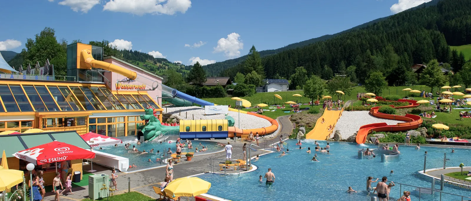 Freibad Wagrain mit Rutschen, Becken, Liegewiese und Bergen im Hintergrund