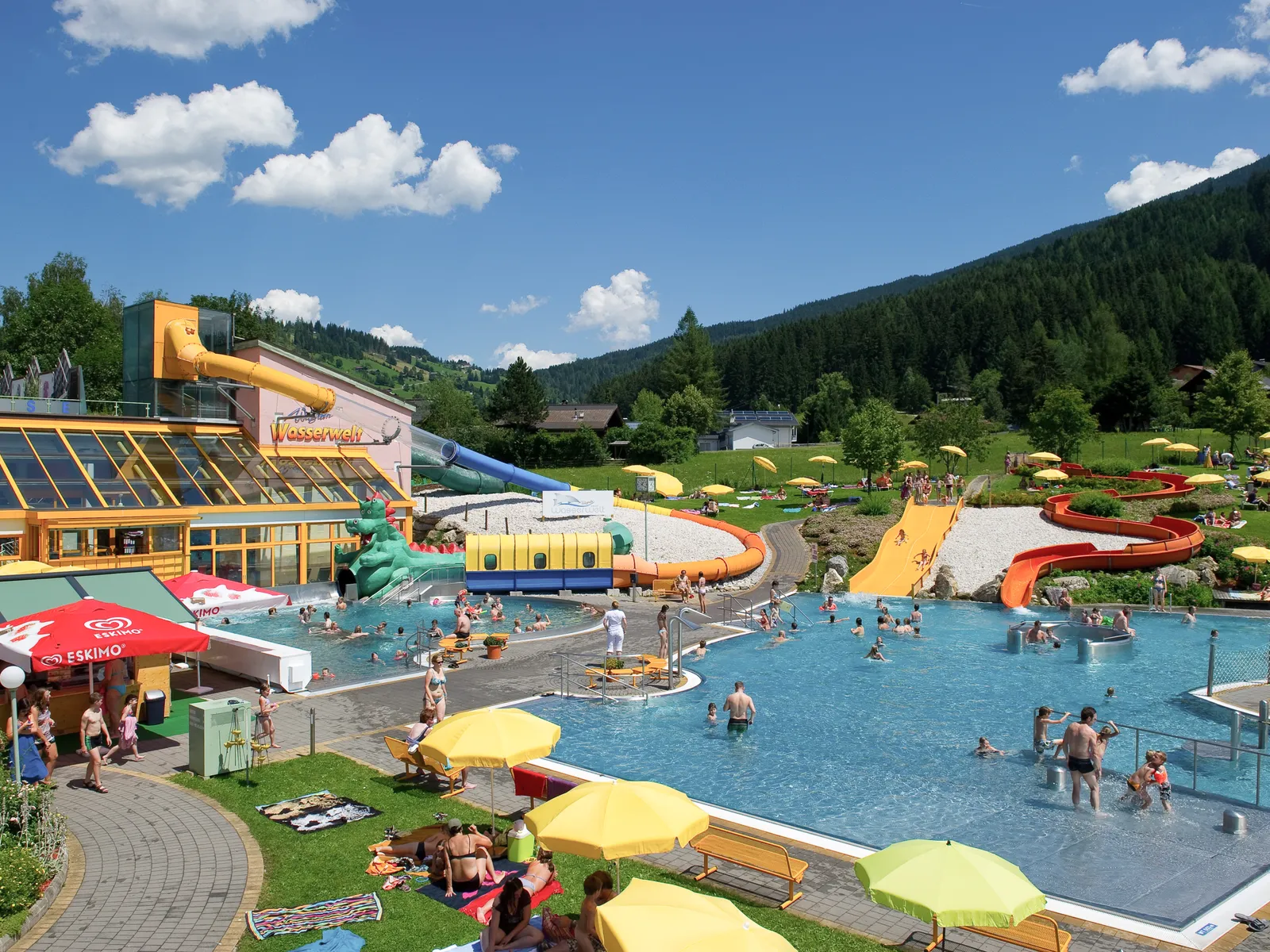 Freibad Wagrain mit Rutschen, Becken, Liegewiese und Bergen im Hintergrund