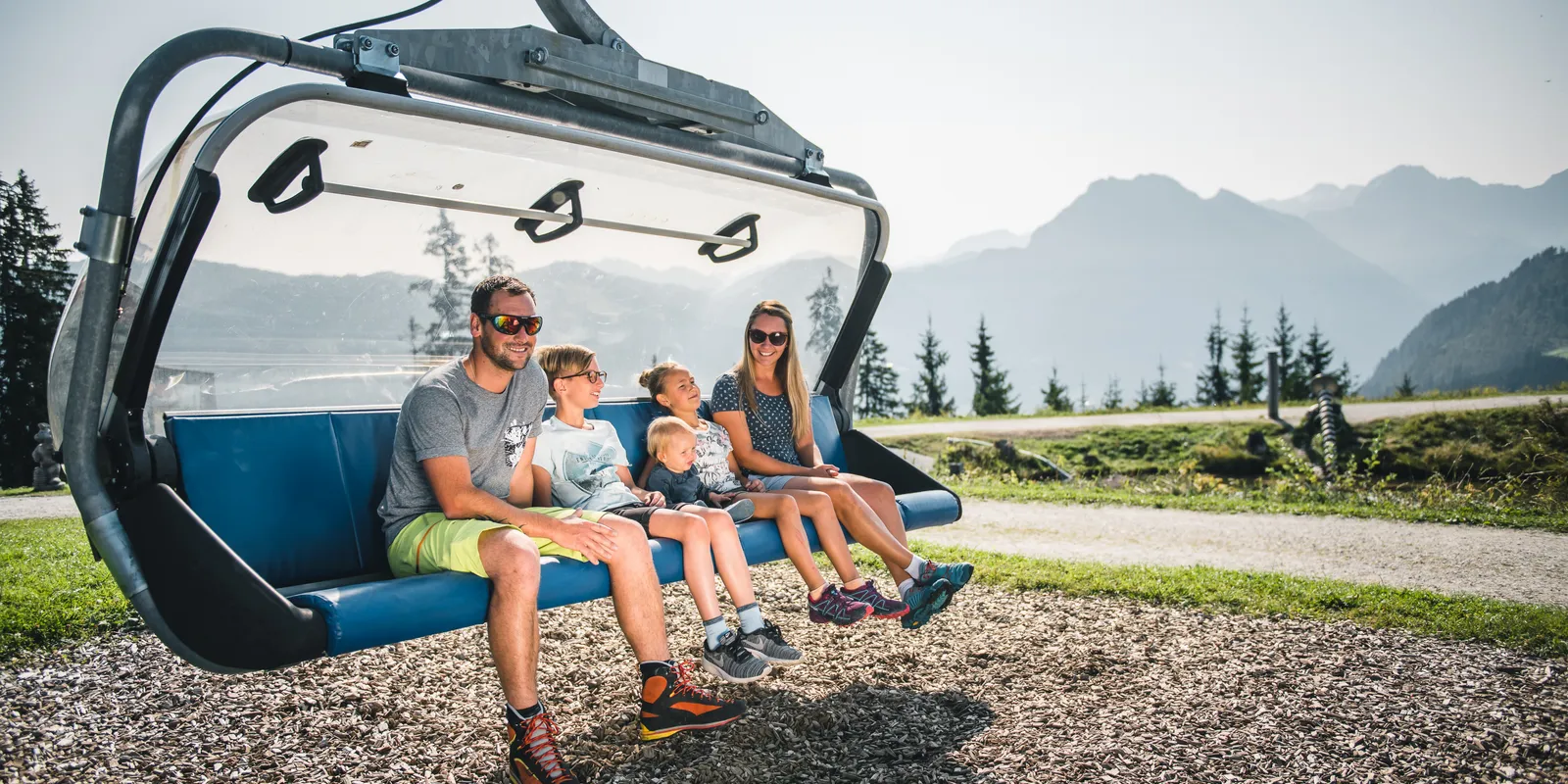 Familie fährt mit Sessellift am Grafenberg in Wagrain vor Bergpanorama