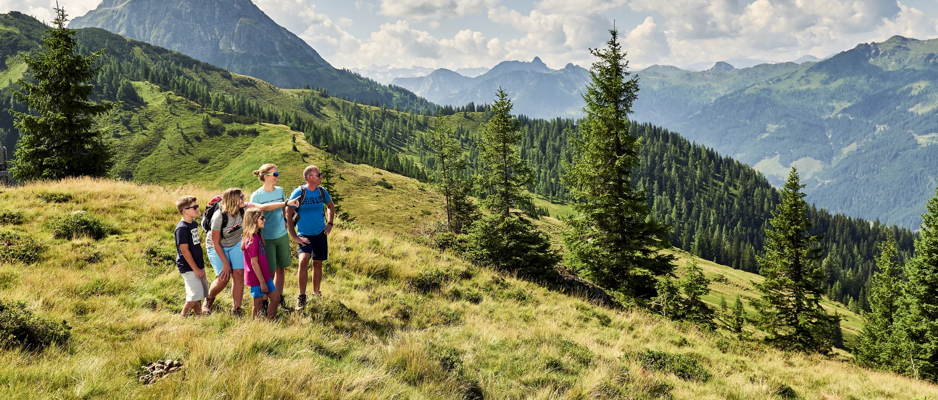 Familie mit Wanderführerin wandert in Wagrain-Kleinarl vor Bergpanorama