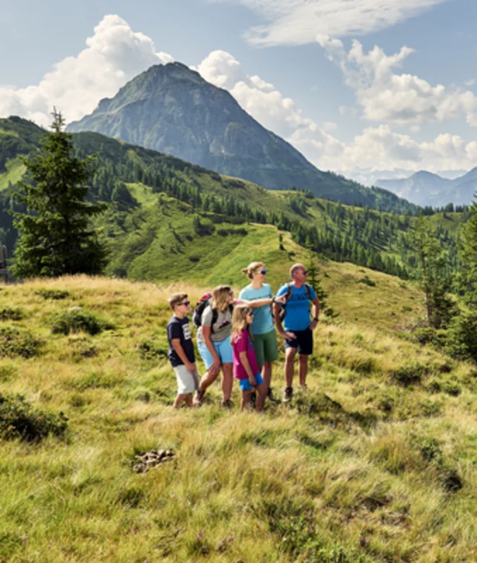 Familie mit Wanderführerin wandert in Wagrain-Kleinarl vor Bergpanorama