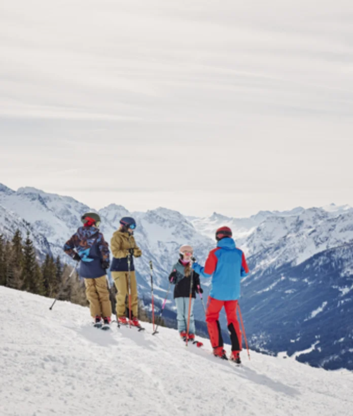 Family with skis on the ski slope in front of a mountain panorama in Wagrain-Kleinarl