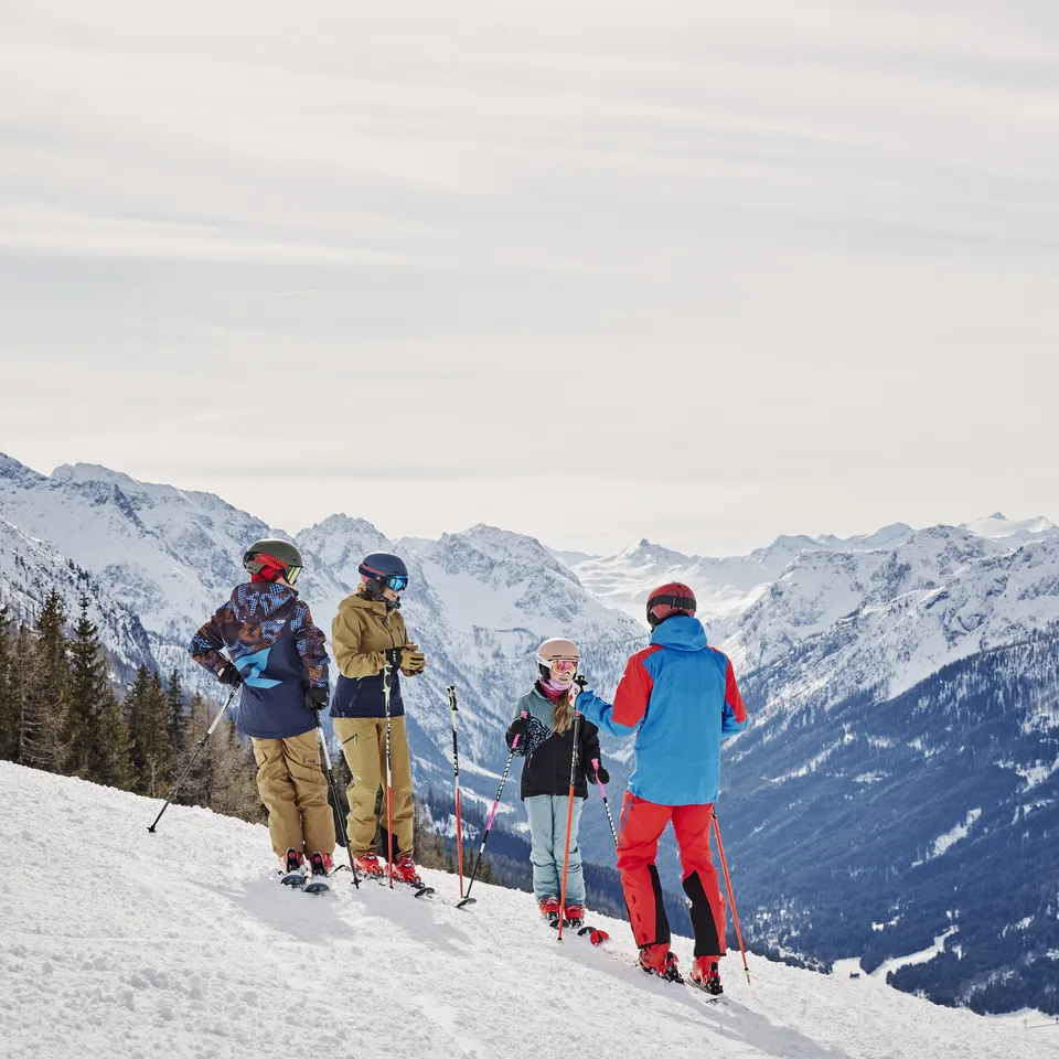 Familie mit Skiern auf Skipiste vor Bergpanorama in Wagrain-Kleinarl