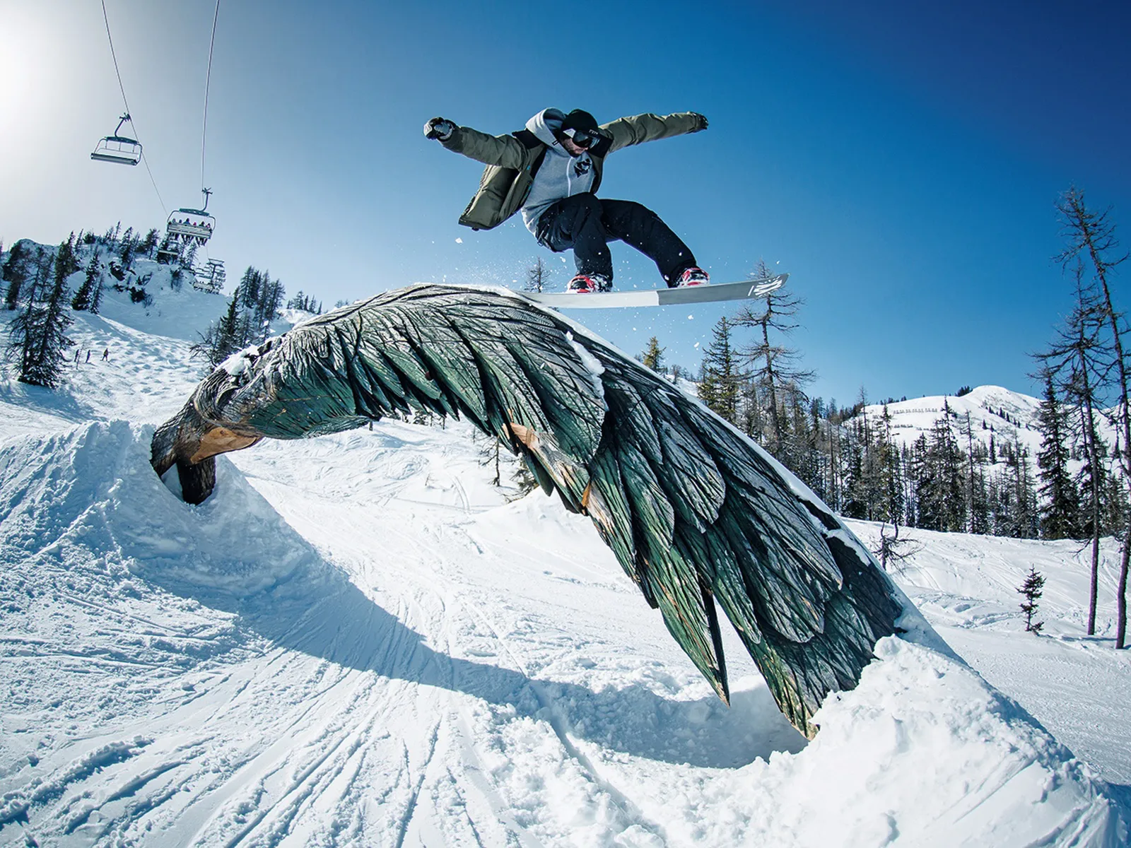 Snowboarder springt über Adler-Skulptur im Absolut Park Flachauwinkl