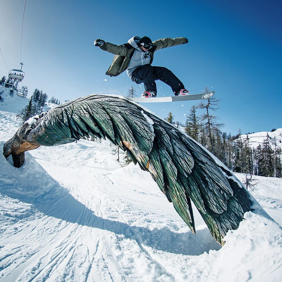 Snowboarder springt über Adler-Skulptur im Absolut Park Flachauwinkl