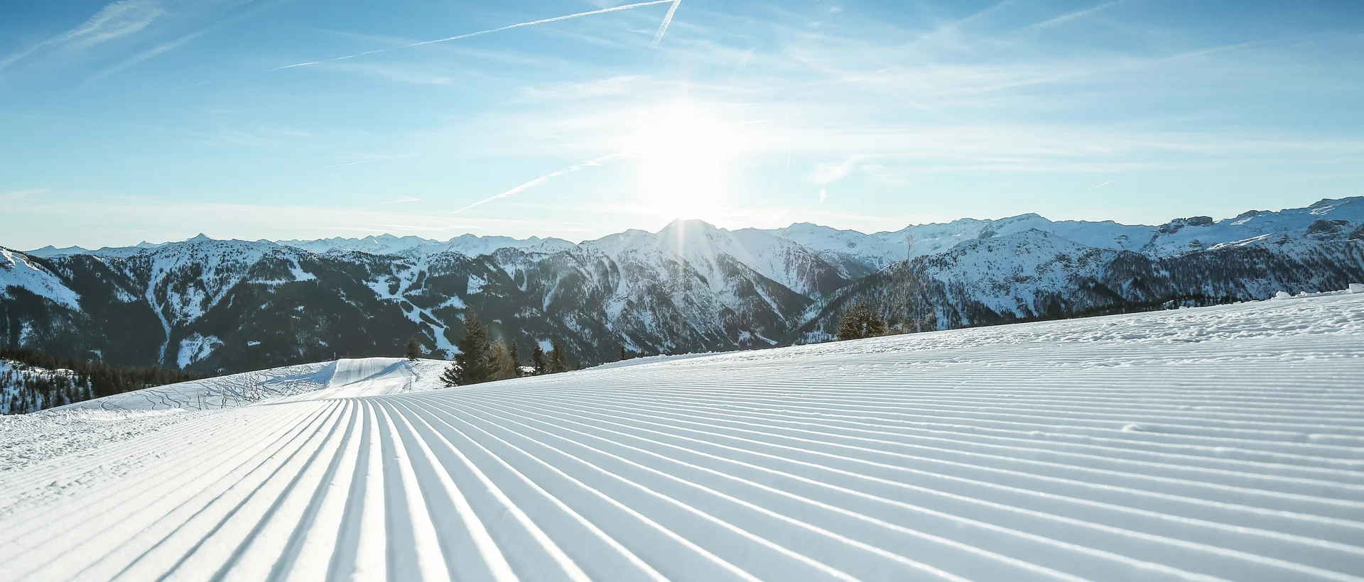 Präparierte Skipiste im Skigebiet Shuttleberg Flachauwinkl-Kleinarl vor Bergpanorama unter blauem Himmel