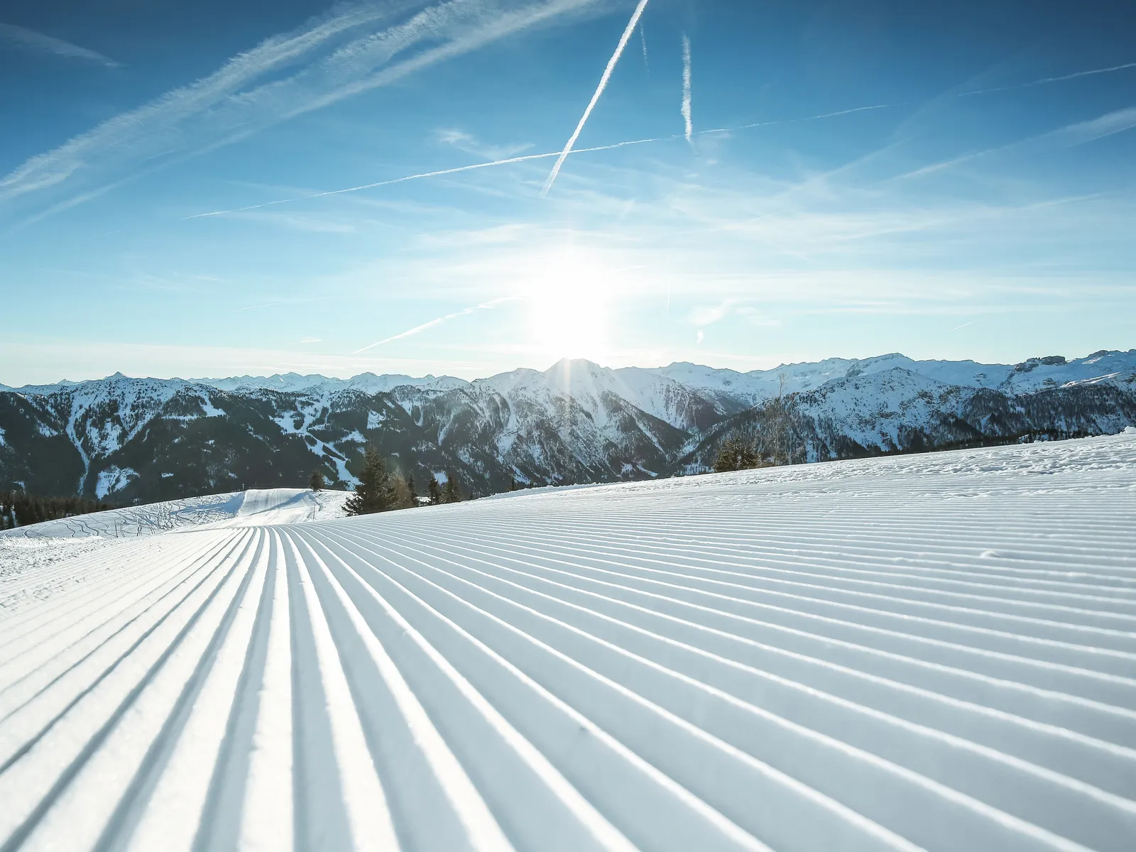 Präparierte Skipiste im Skigebiet Shuttleberg Flachauwinkl-Kleinarl vor Bergpanorama unter blauem Himmel