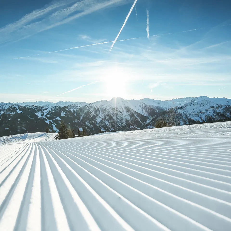 Präparierte Skipiste im Skigebiet Shuttleberg Flachauwinkl-Kleinarl vor Bergpanorama unter blauem Himmel