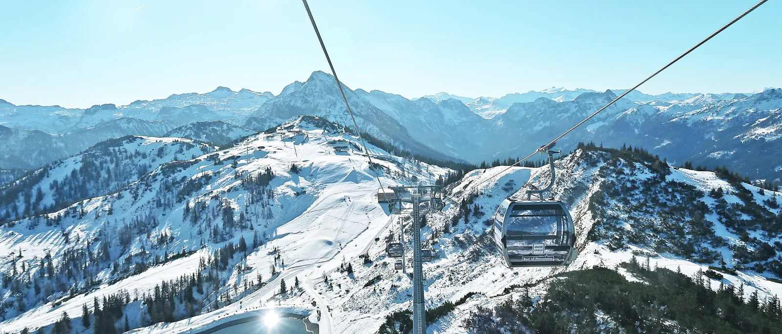 Seilbahn über schneebedeckte Berge in der Salzburger Sportwelt bei strahlendem Sonnenschein