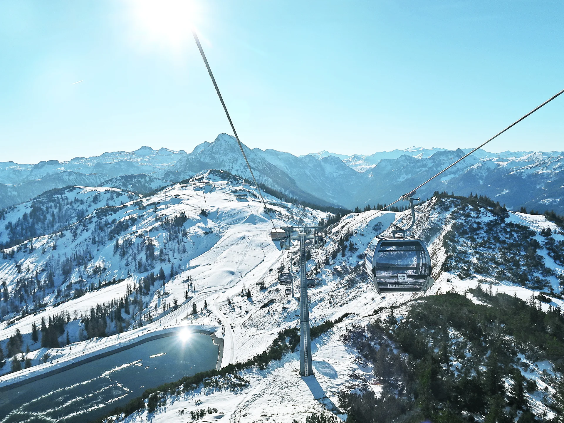 Seilbahn über schneebedeckte Berge in der Salzburger Sportwelt bei strahlendem Sonnenschein