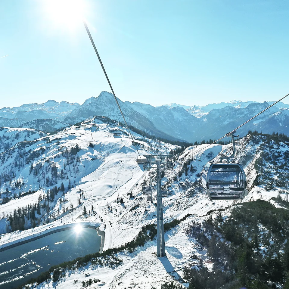 Seilbahn über schneebedeckte Berge in der Salzburger Sportwelt bei strahlendem Sonnenschein