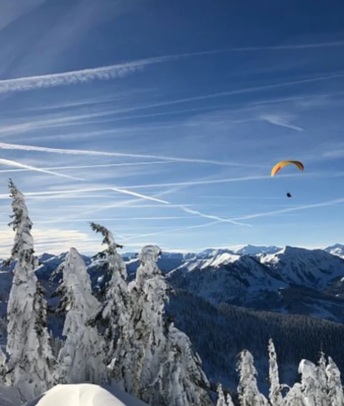 Paragleiter fliegt über verschneite Berge im Winterhimmel von Wagrain-Kleinarl