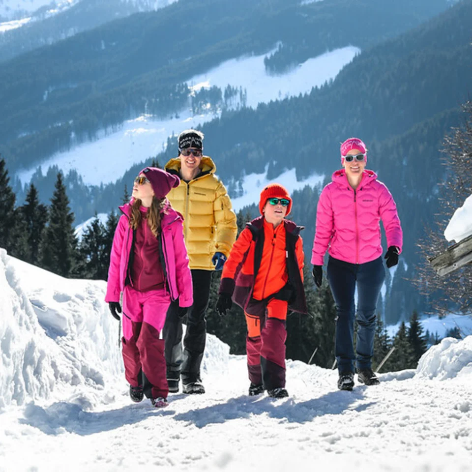 Family hikes through snowy mountain landscape in winter