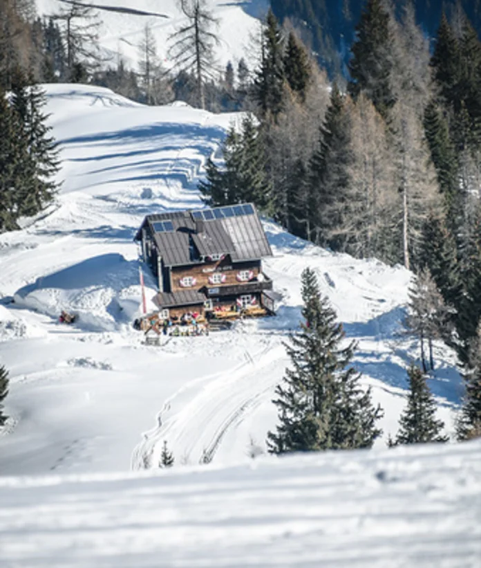 Schneebedeckte Berghütte umgeben von Bäumen im Winter