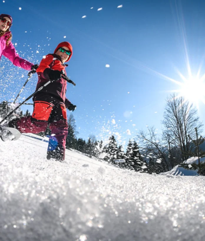 Zwei Personen beim Schneeschuhwandern im Schnee, sonniger Wintertag