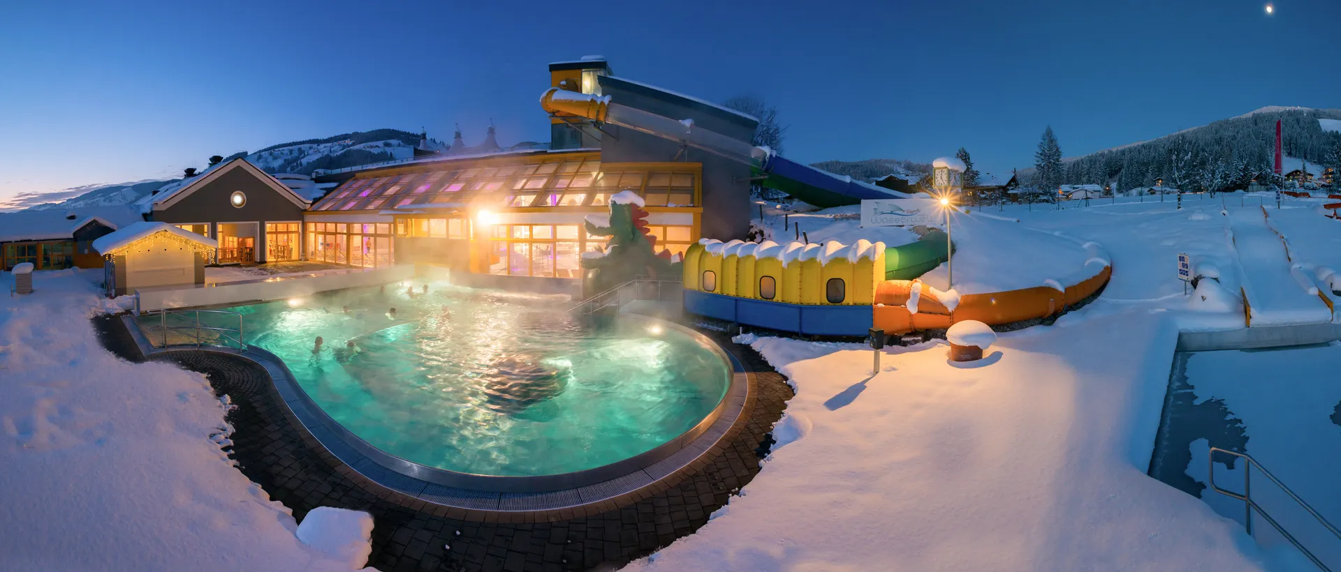Outdoor pool in winter with steam, water slide and snow im Sporthotel Wagrain