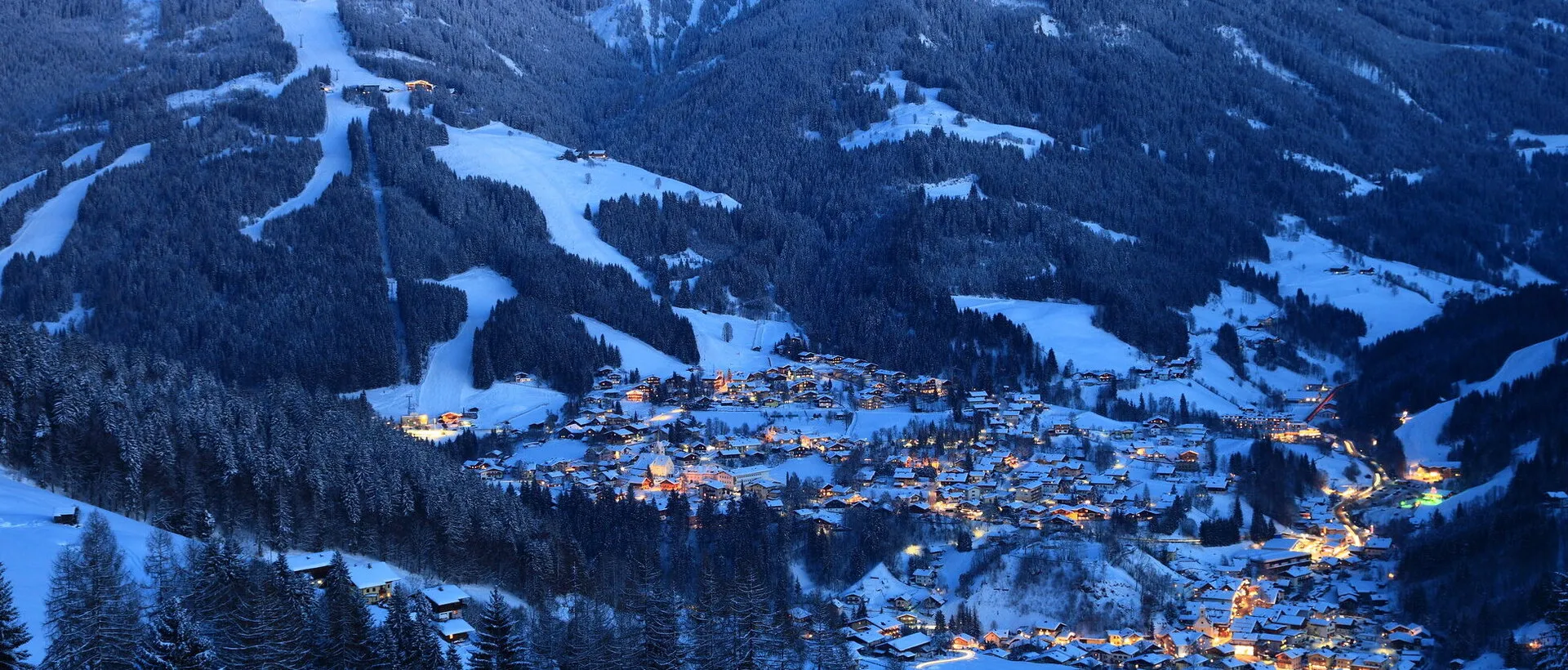 Winter mountain landscape with illuminated village in the valley
