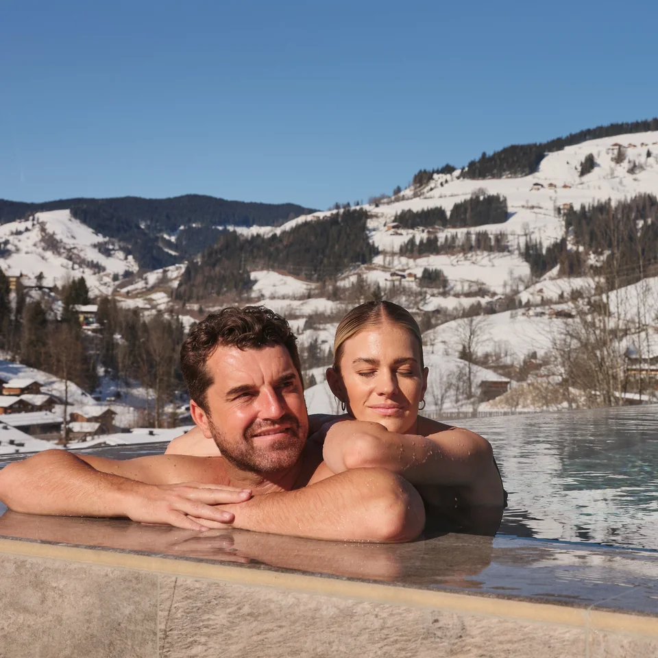 Paar im Pool vor verschneiter Berglandschaft