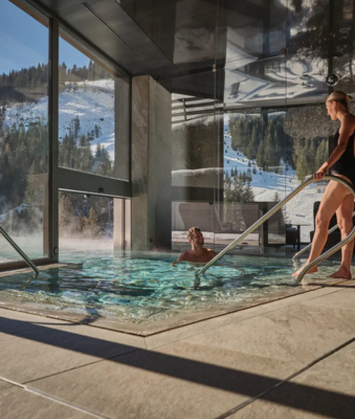 Frau steigt aus Pool im Sporthotel Wagrain mit Blick auf verschneite Berge