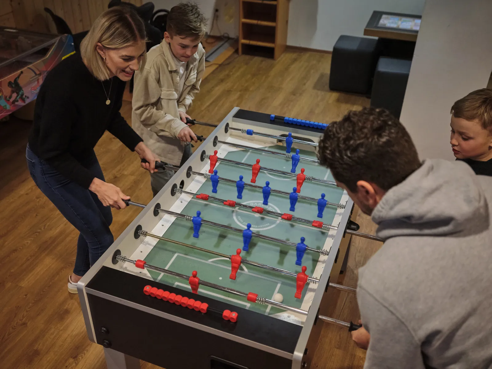 Frau und zwei Jungen spielen Tischfußball