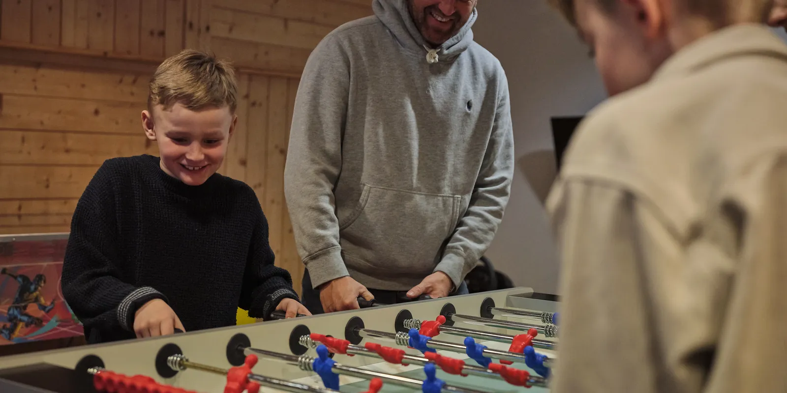 Father and two sons playing table football indoors